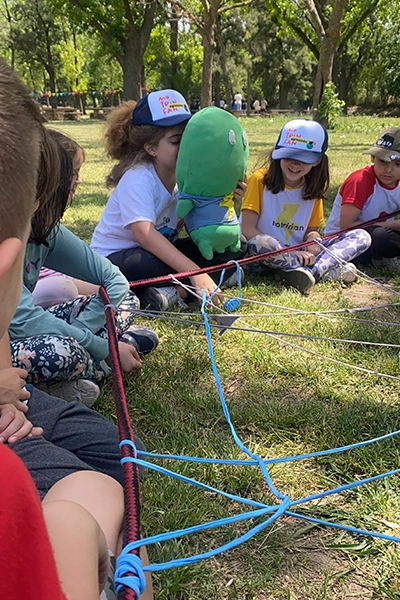nenes sentados en ronda, con peluche mascota motri y tirando de una red