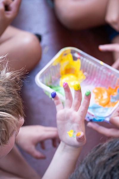 mano de un nene con las yemas de los dedos pintadas de colores